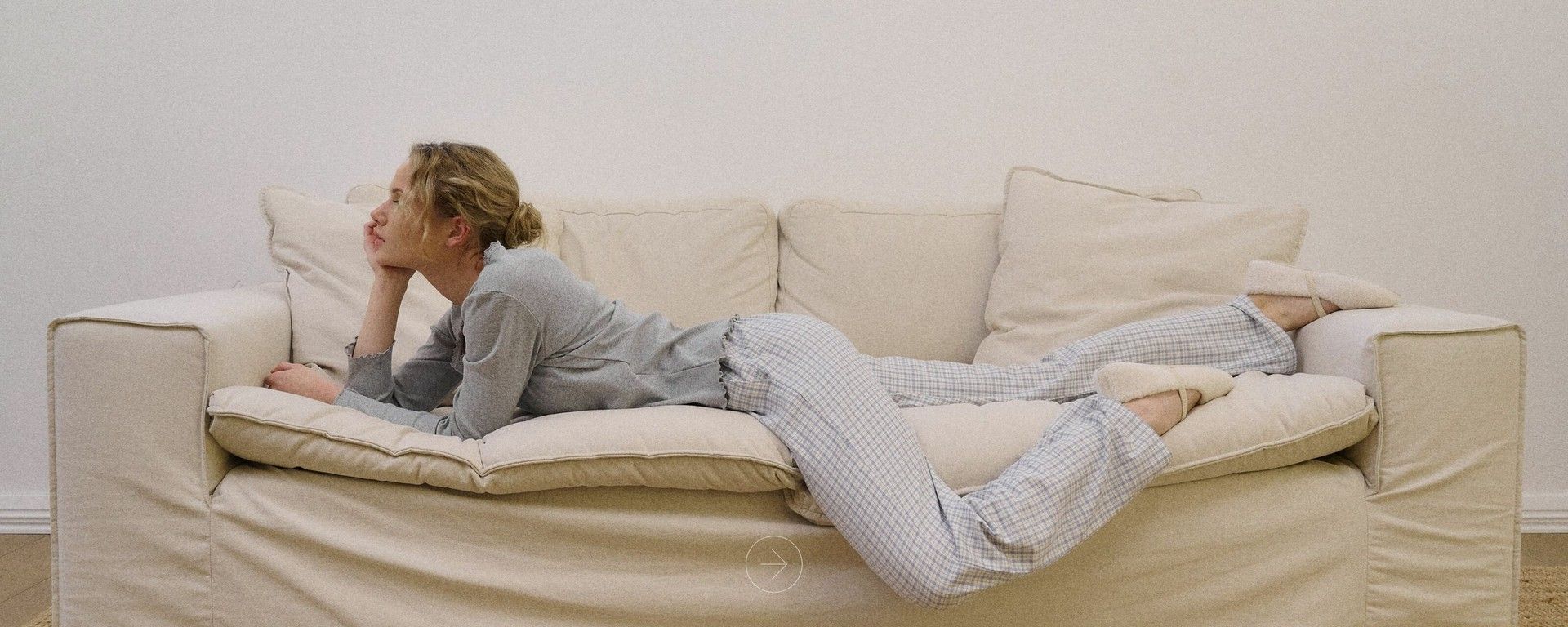 Femeie relaxându-se pe o canapea albă îmbrăcată în pijama confortabilă de bumbac